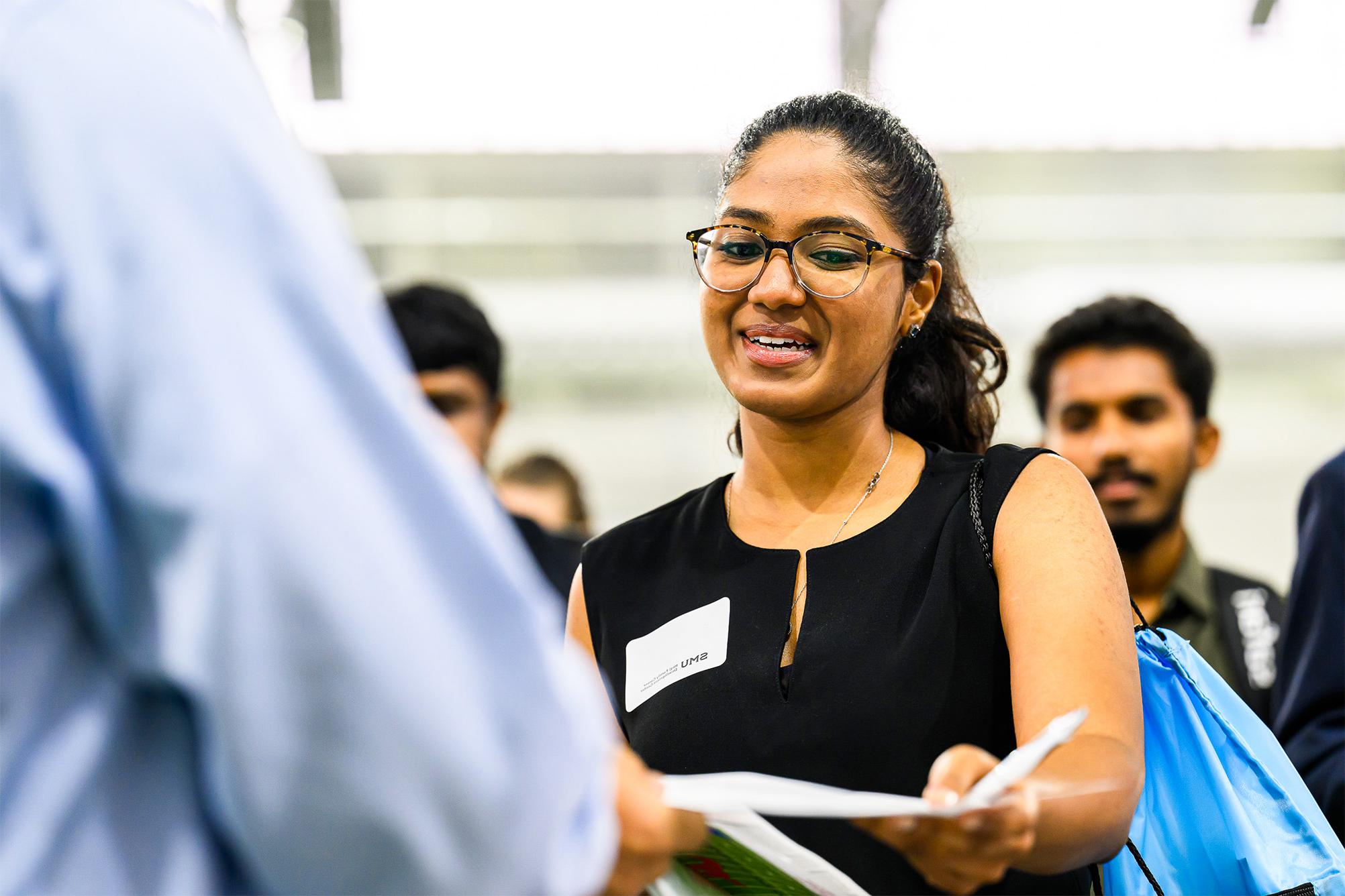 student handing piece of paper to employer at Career Fair